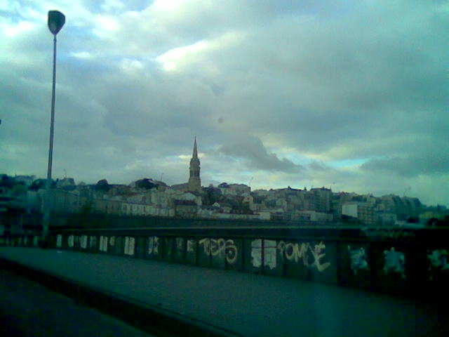 cloudy skies over the old city with graffiti on the bridge