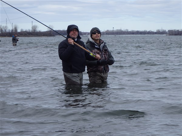 two people standing in water holding a fishing rod