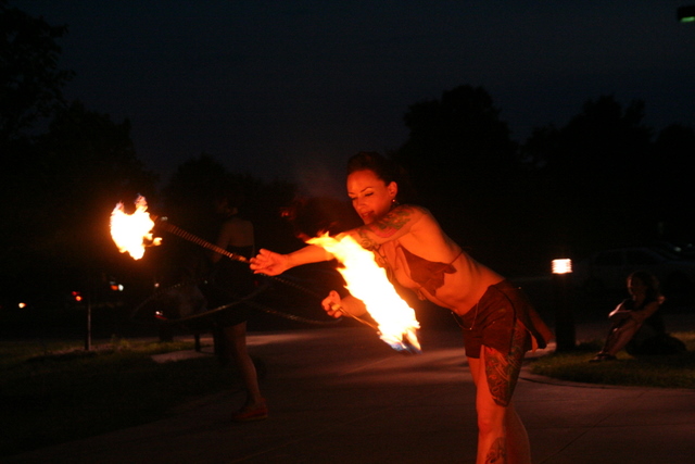a person holding a pole while spinning fire torches