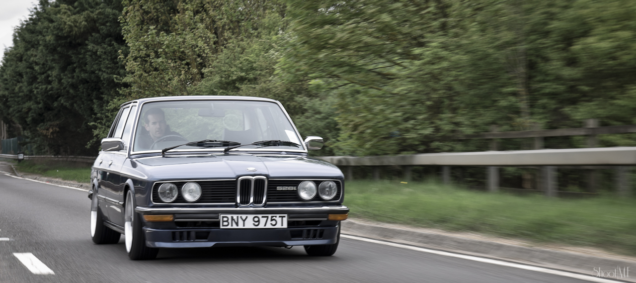 bmw car moving on a roadway in a wooded area