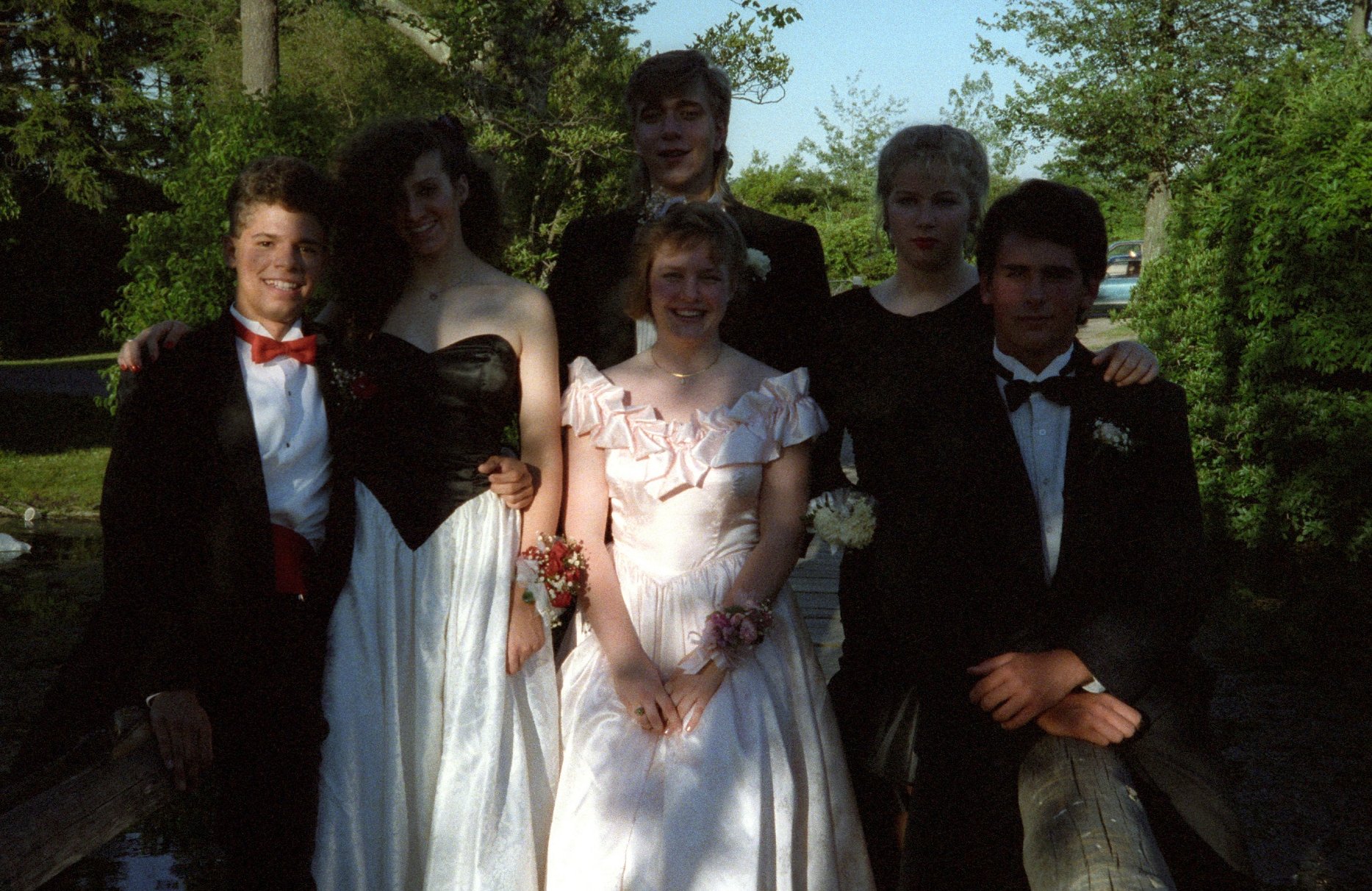 a group of people in prom gowns and tuxedos standing next to each other