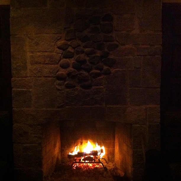 a fireplace with fire in it and rocks on the wall