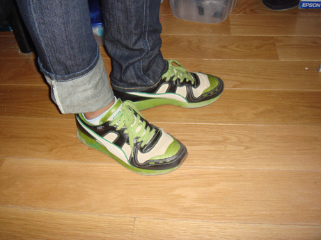 person standing on wooden floor in blue jeans and green sneakers