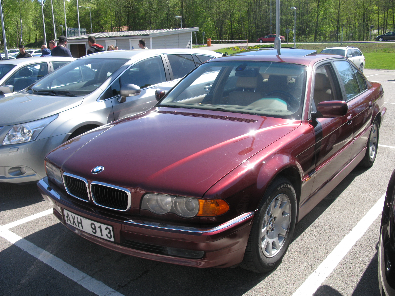 a maroon bmw in a parking space between two other cars