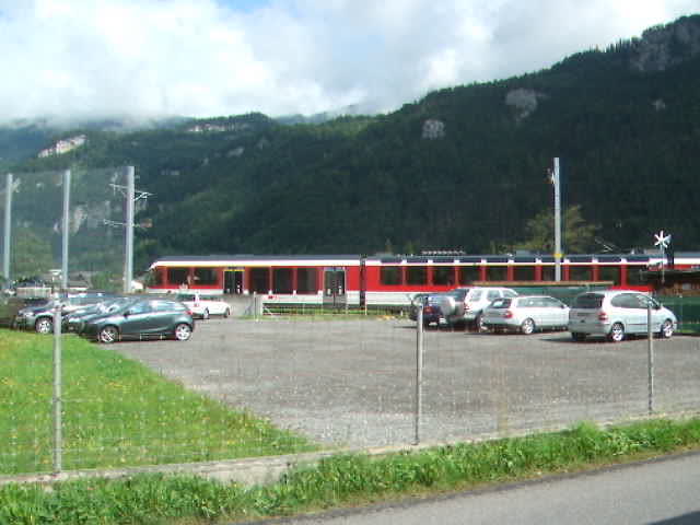 cars are parked in an empty parking lot beside a train