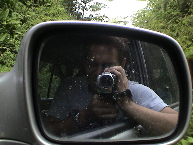 the rear view mirror of a car shows a man taking a po