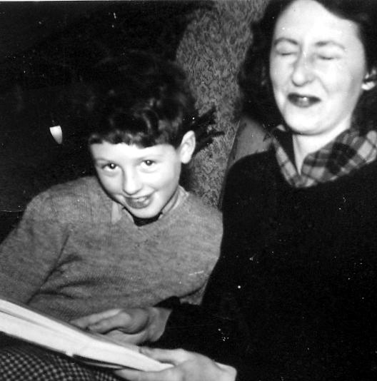 a  with a book in his hand and an older woman smiling behind him