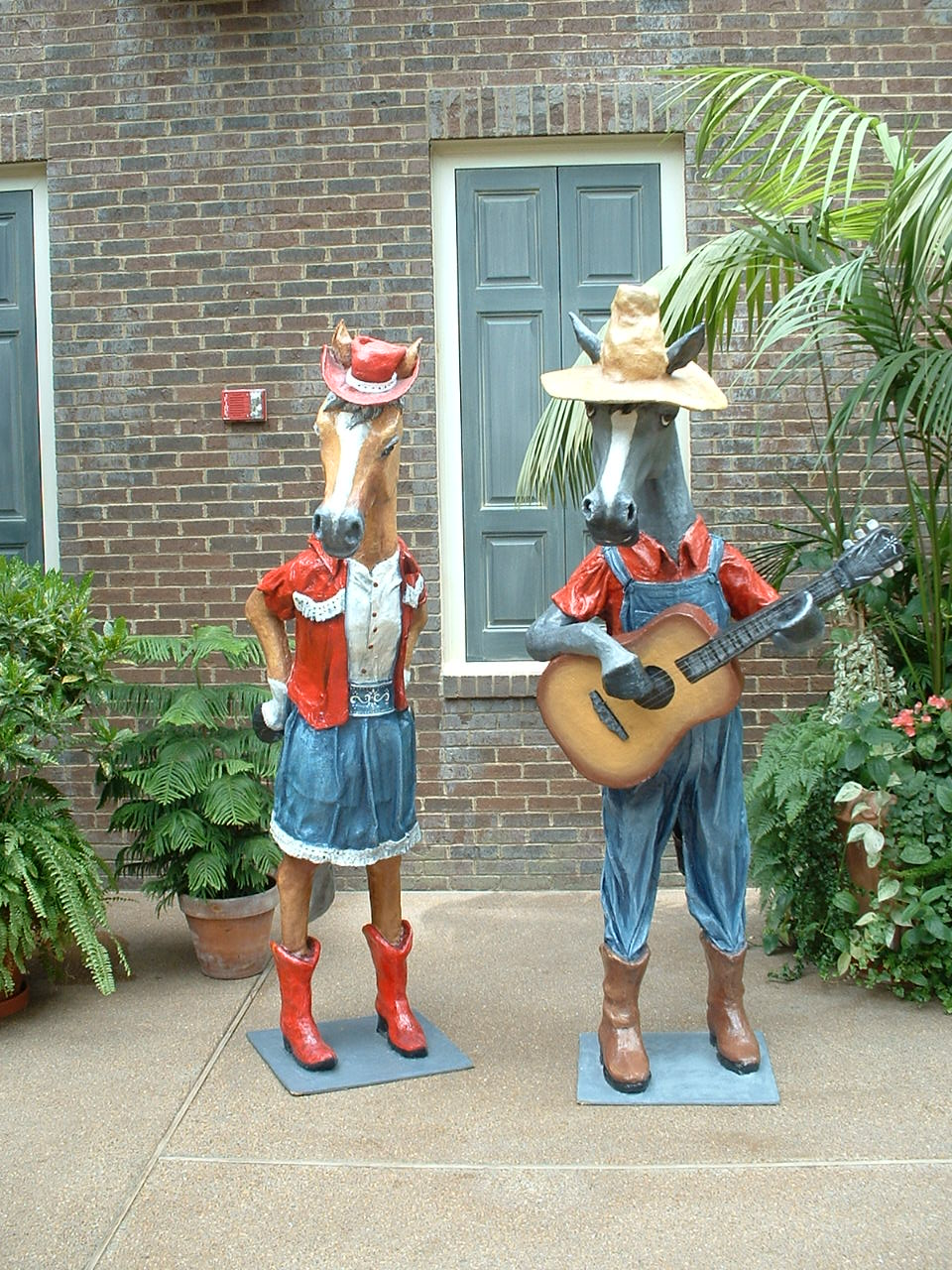 two horses statues in cowboy outfits playing instruments