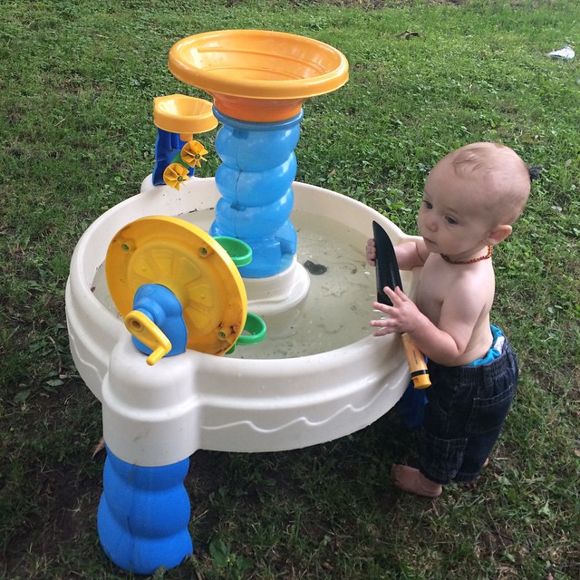a little boy standing next to a small fountain