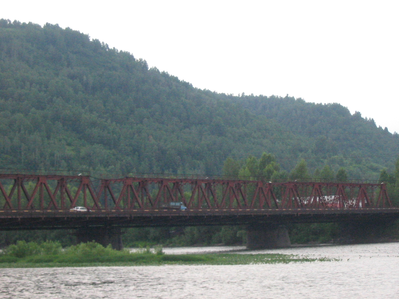 a large bridge over water next to green trees