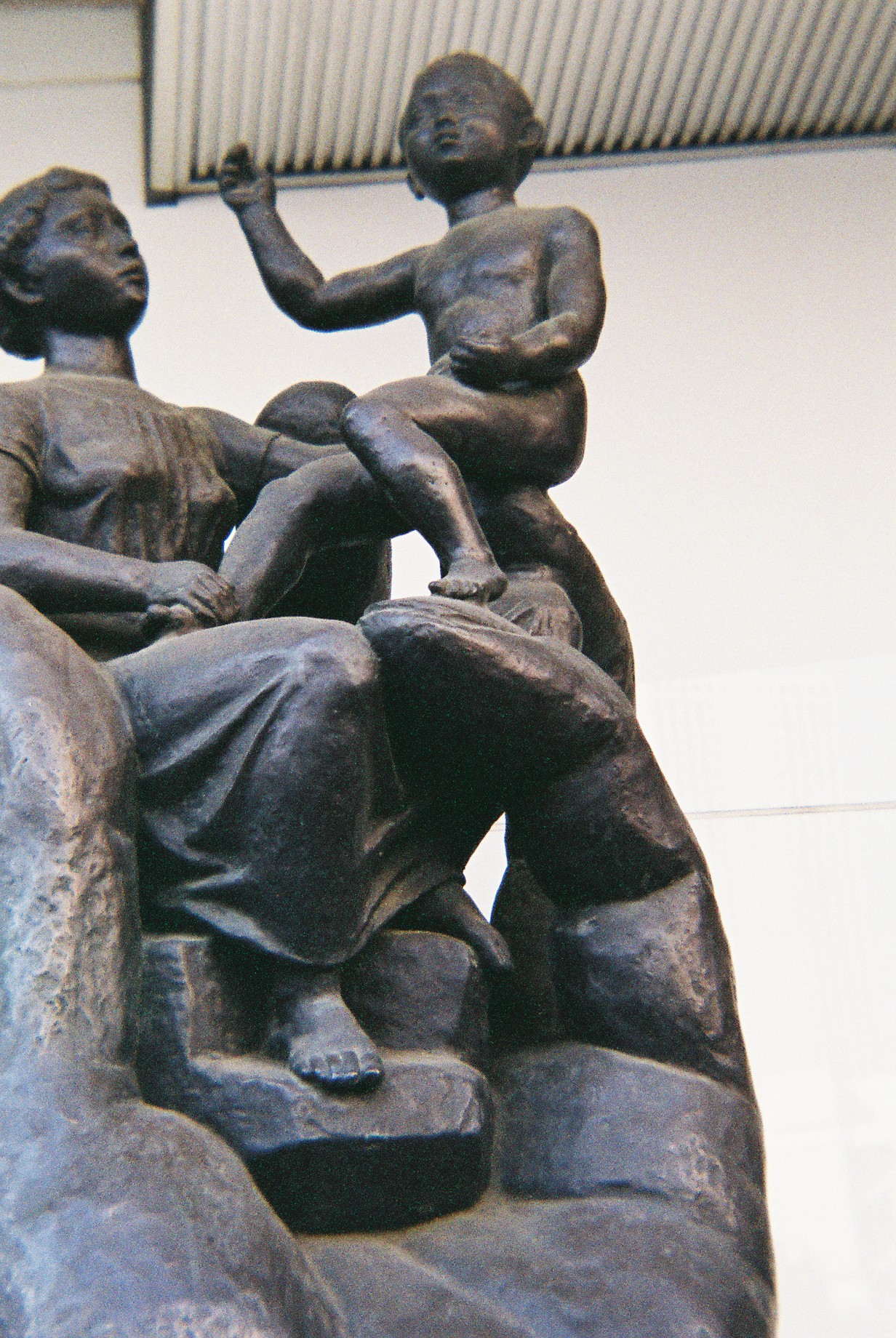 a bronze sculpture of two children standing on a rock