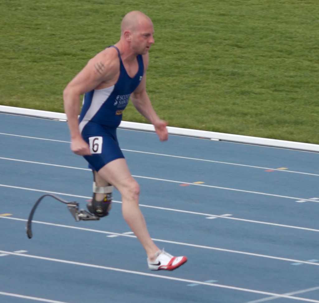 a male athlete running on a blue track