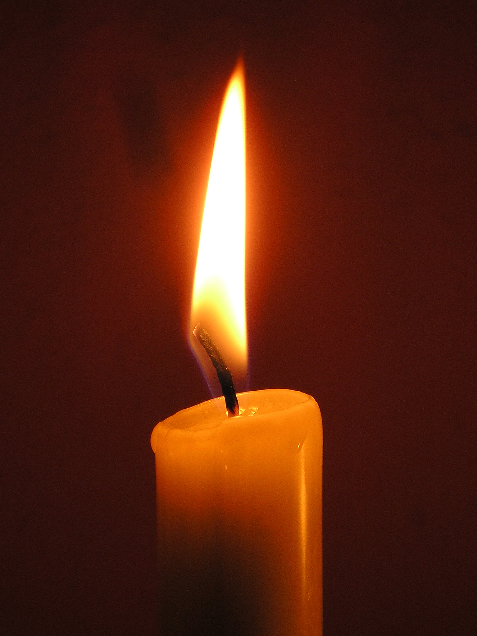 a single white candle with the light burning