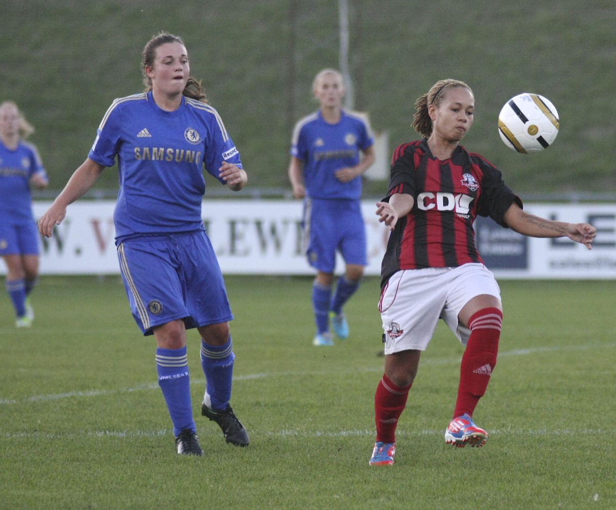 two girls playing soccer on a grassy field