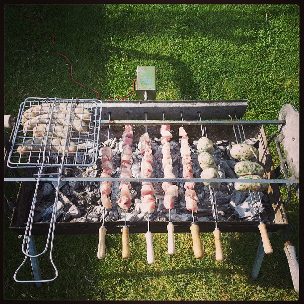 food on the grill in the grass near a field