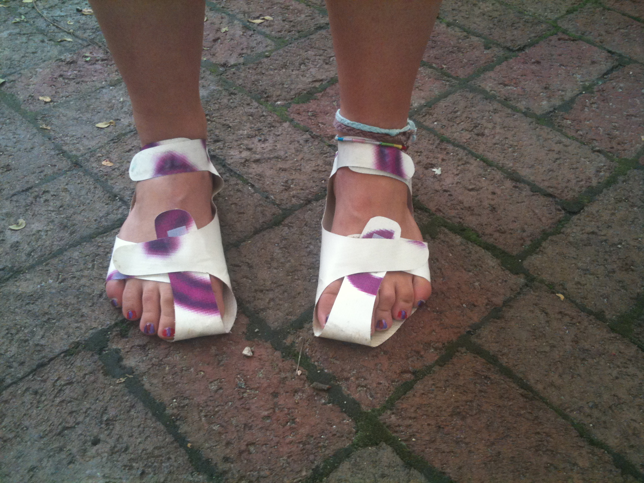 a person's foot with white sandals and purple patterns