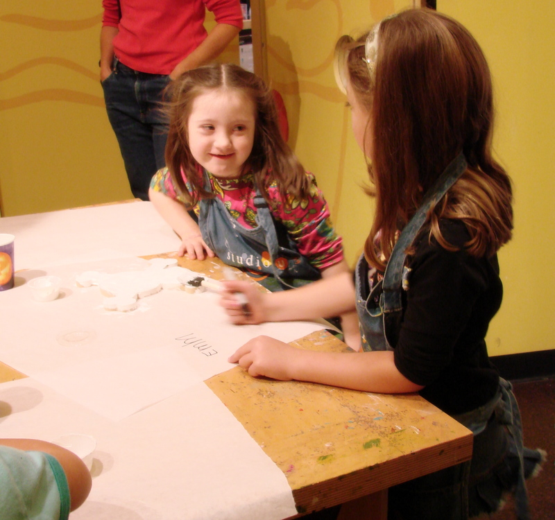 two girls sitting at a table together with doughnuts