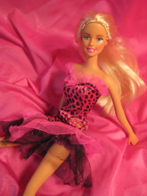 barbie is laying on a pink blanket