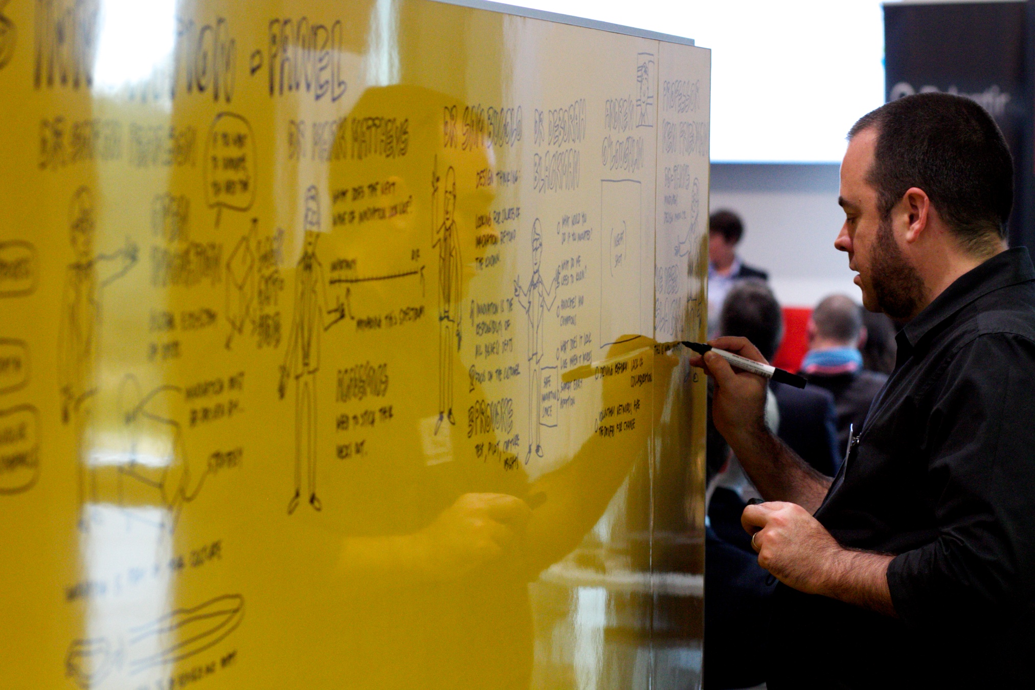 man writing on a board with yellow marker