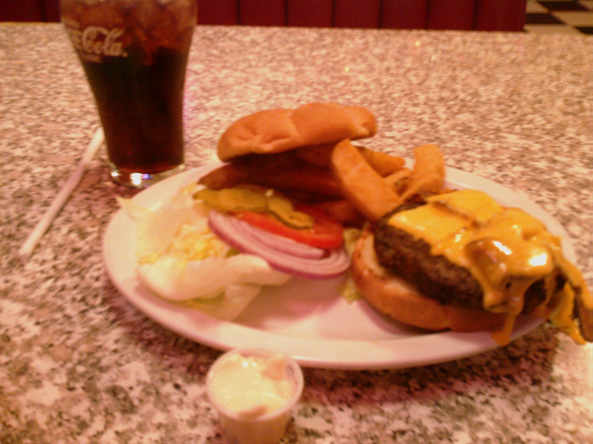cheeseburger on a white plate with a drink and drink