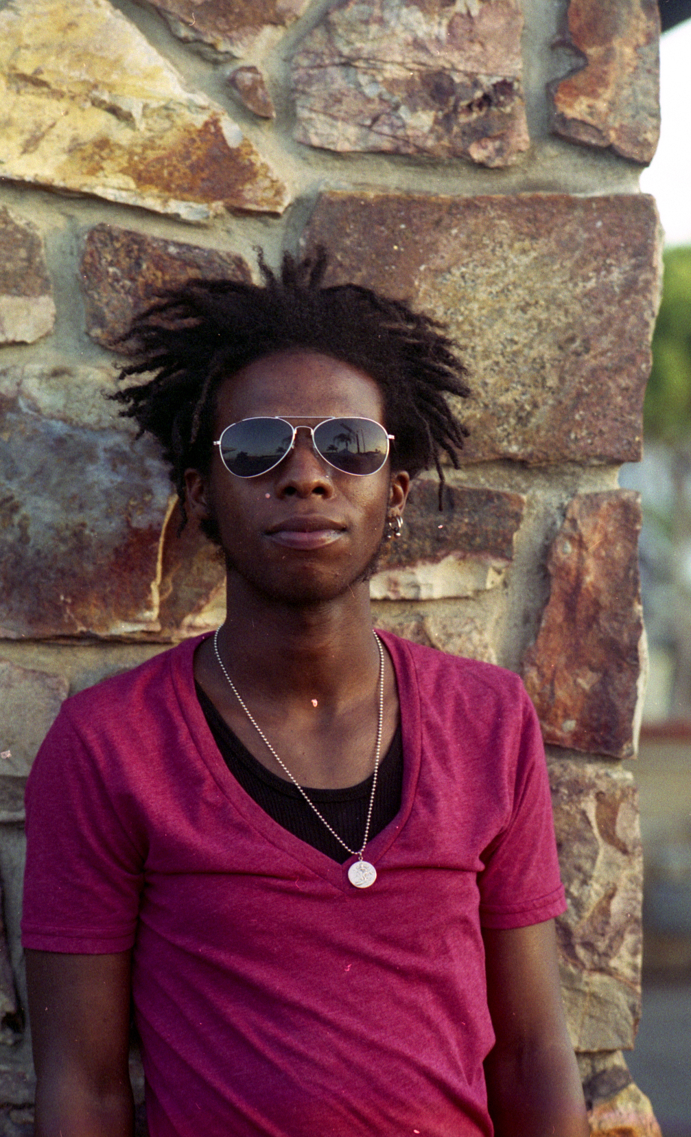 a person that is wearing sunglasses near a brick wall