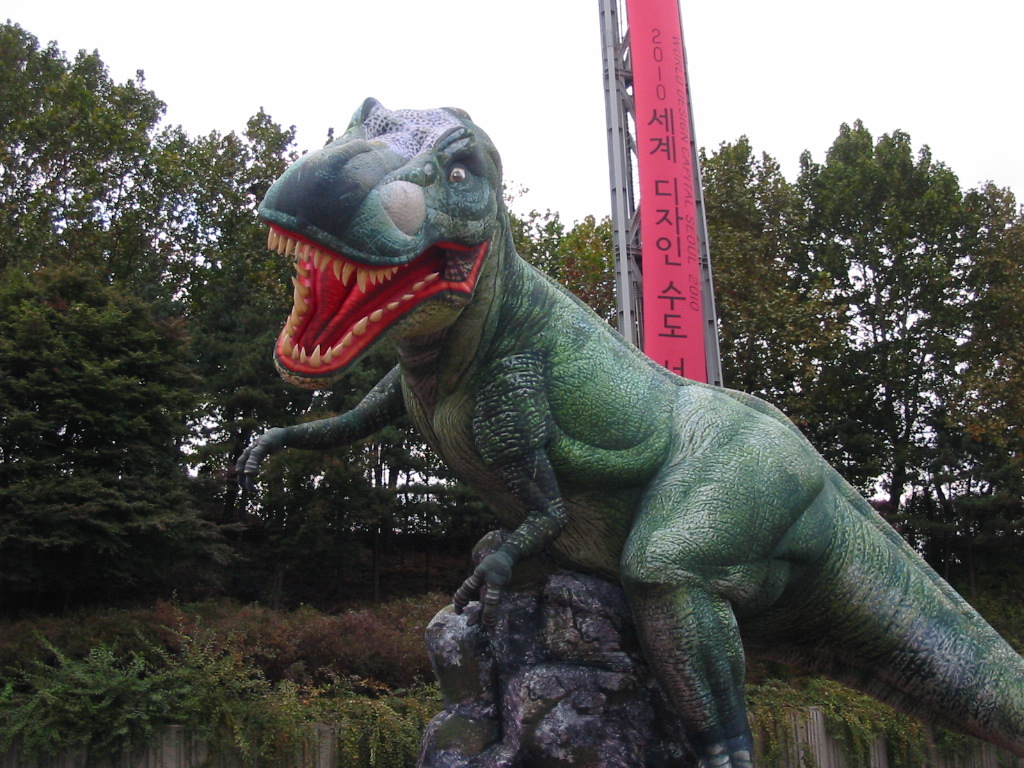 an adult dinosaur statue in front of a large oriental sign