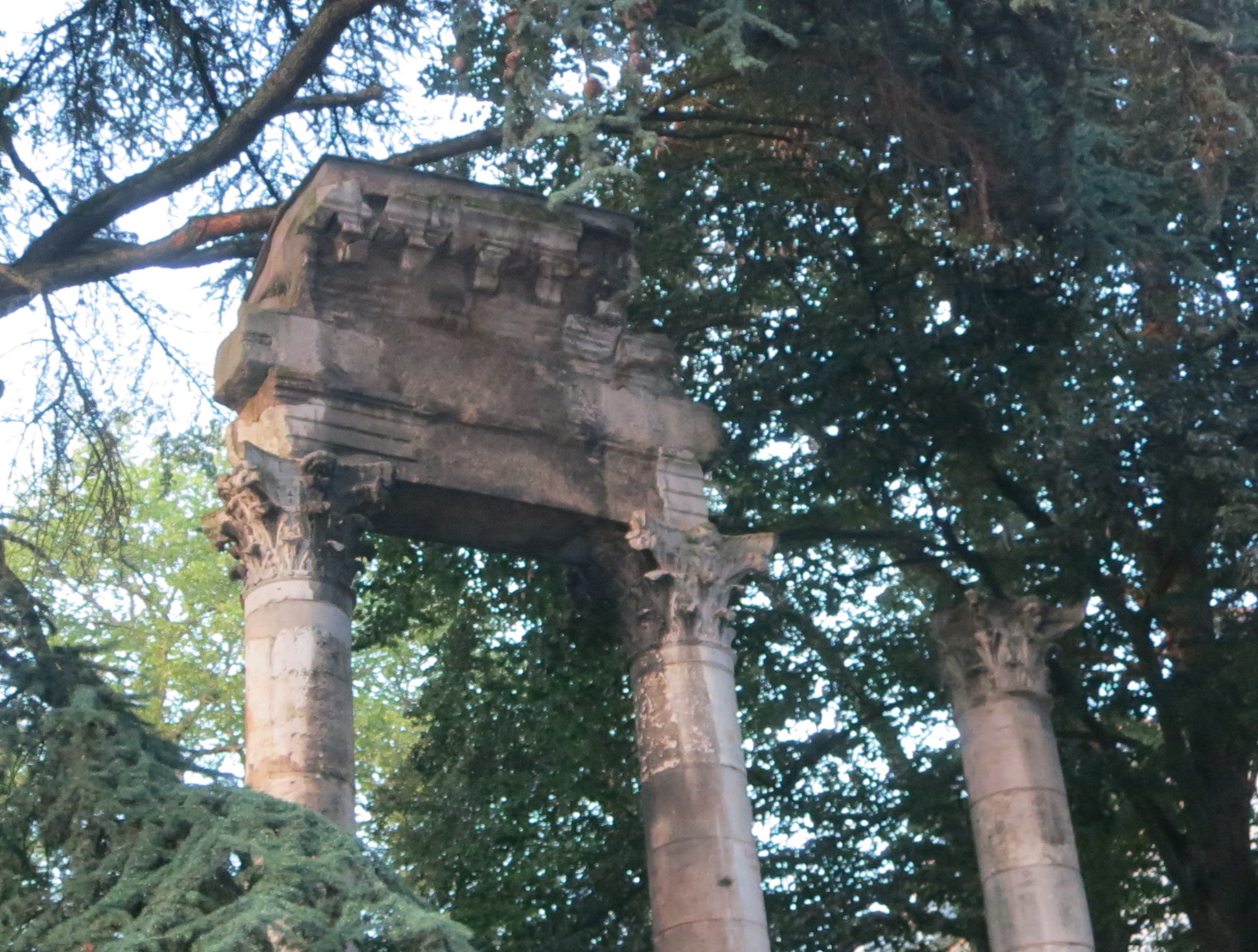 a stone archway between two columns surrounded by trees