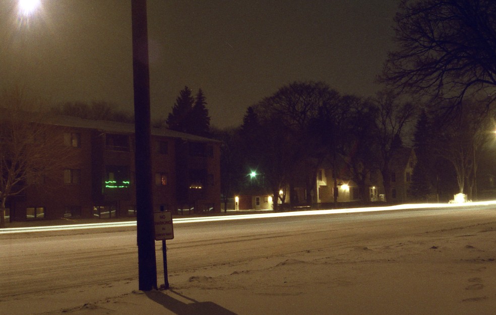 snowy street with snow covered sidewalk and light posts