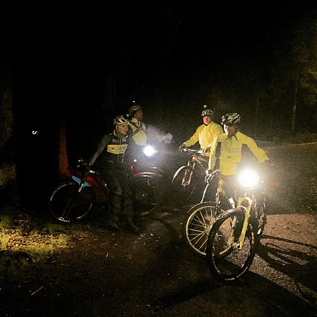 two people are riding on bicycles at night