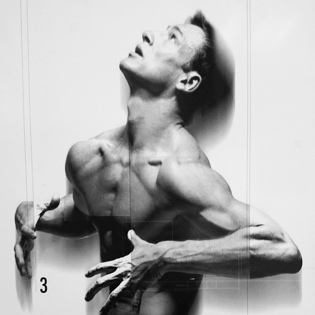 a man stretching his arms out in front of a white wall