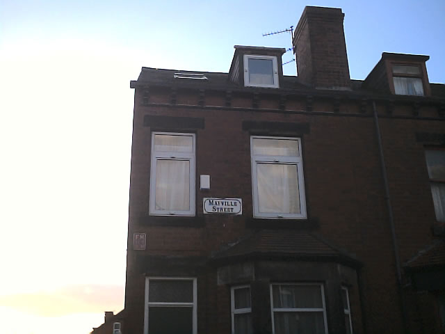 a tall brick building has windows and a street sign on it