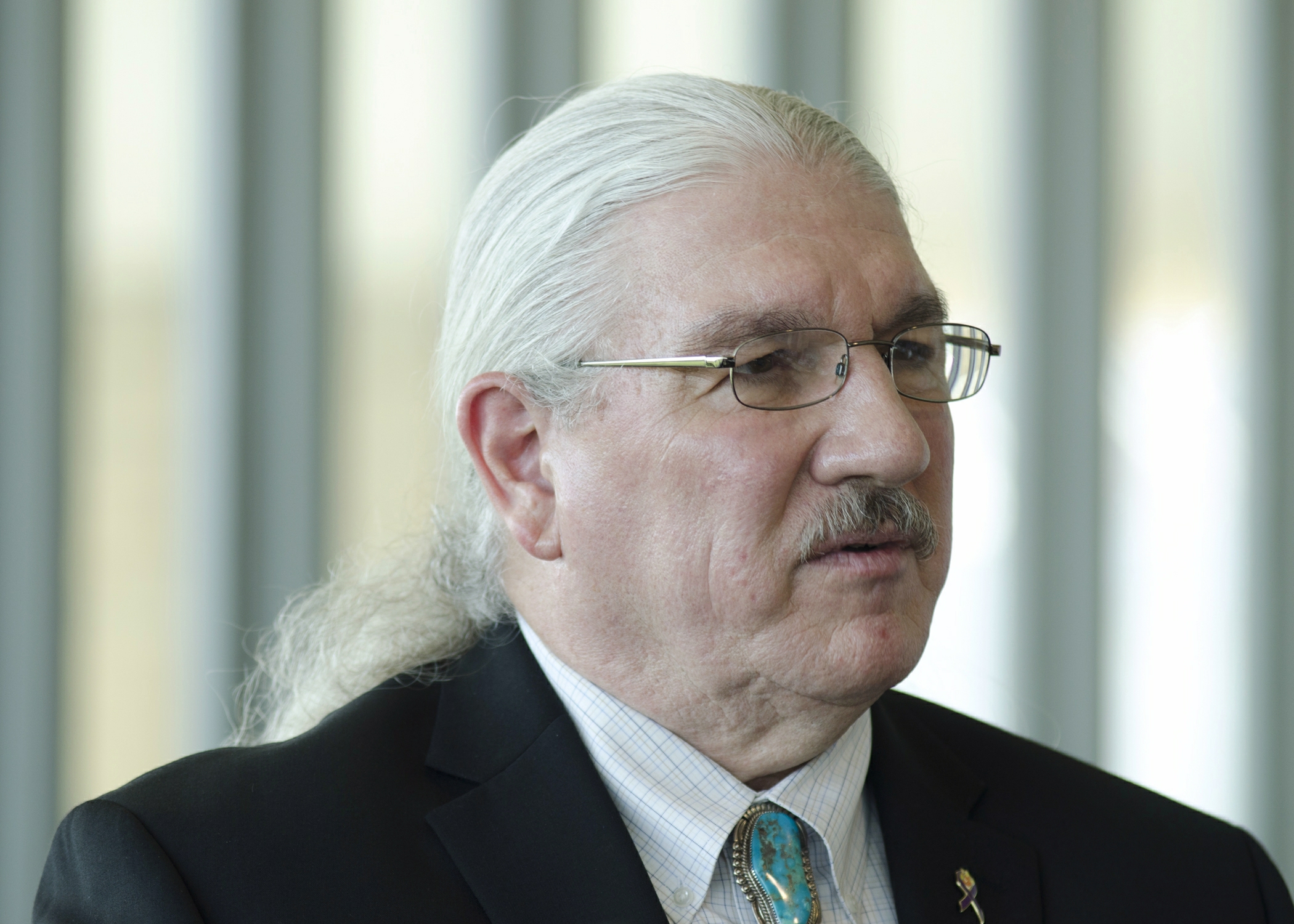 an older gentleman in a suit looks away from the camera