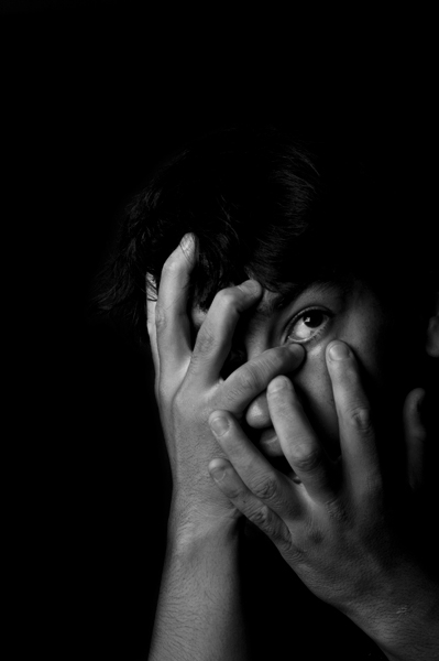 a black and white pograph of a person covering his face with their hands