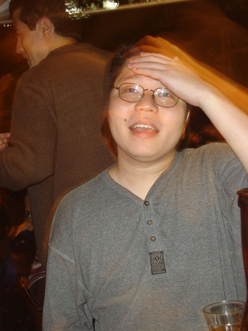 a young man in glasses holding his head to the side