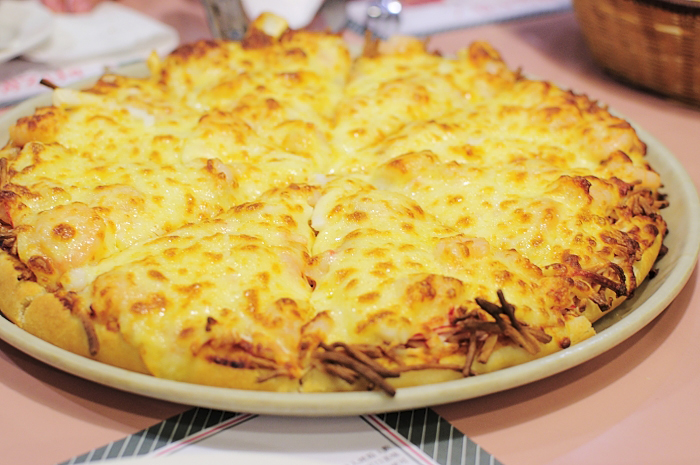 a plate holding a cheesy pizza and plates of forks