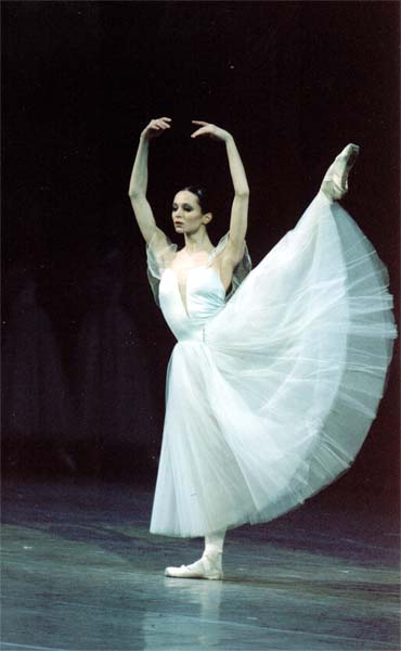 a woman standing on one leg with her , dressed in a white tulle