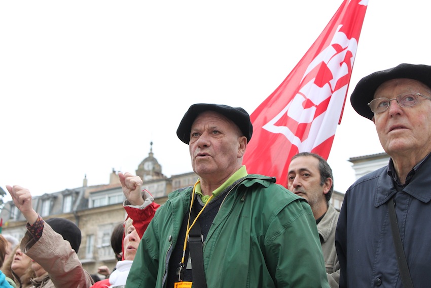 men in green jackets, hats and glasses, standing in front of a crowd