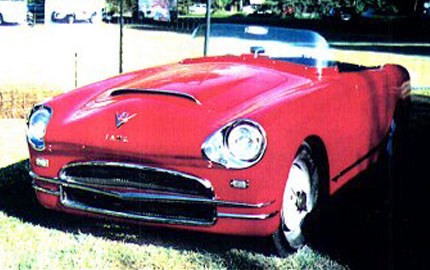 a red convertible car parked in the grass