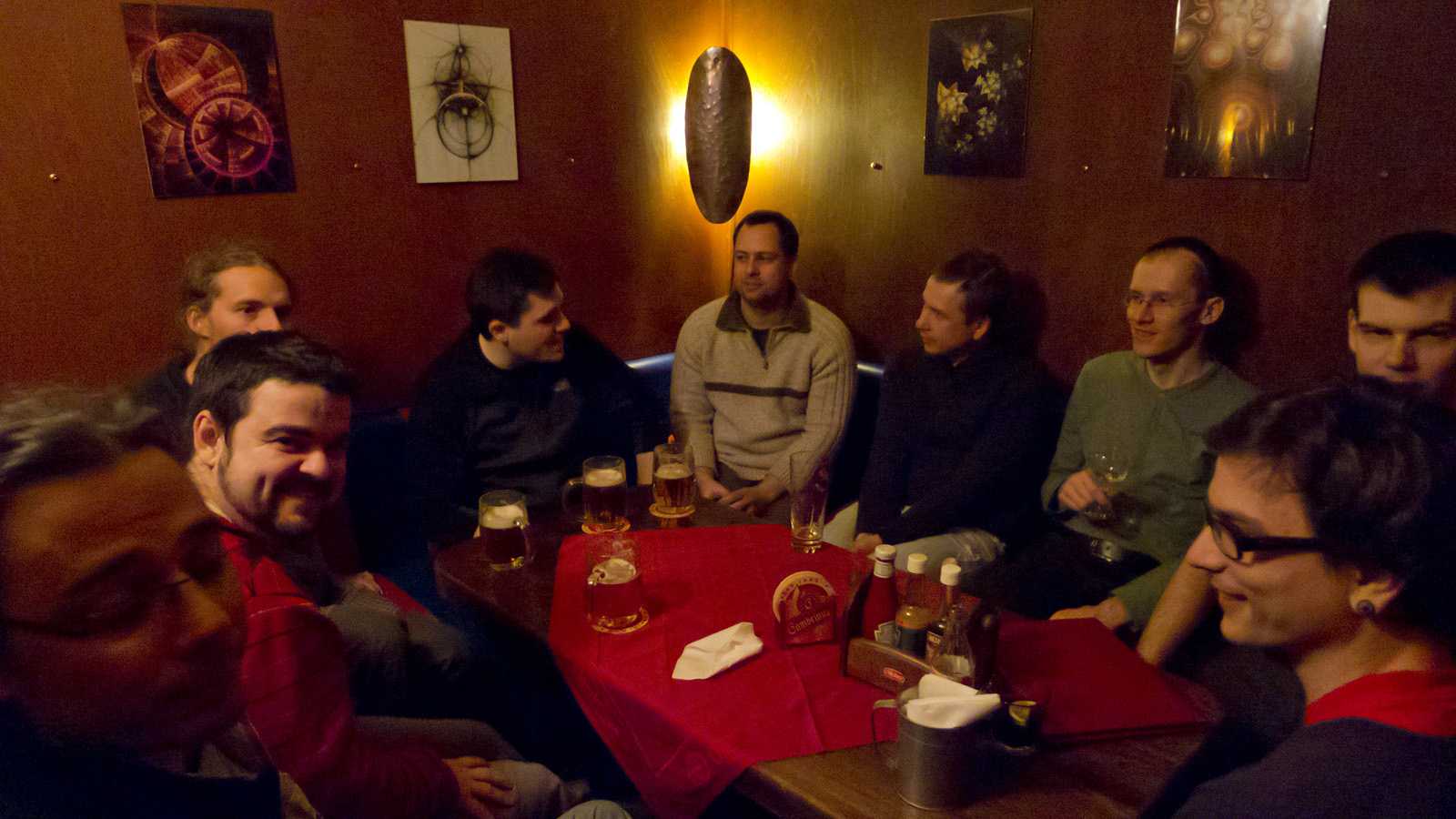 several people gathered together around a table with bottles and glasses