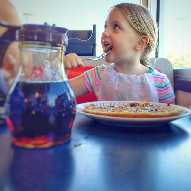 the little girl is eating her food with a water bottle