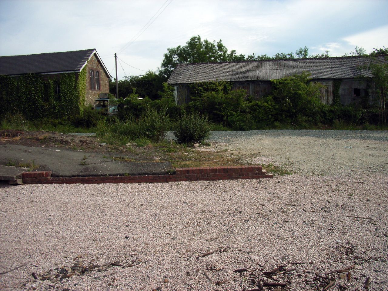 an empty street with dirt on it near a few houses