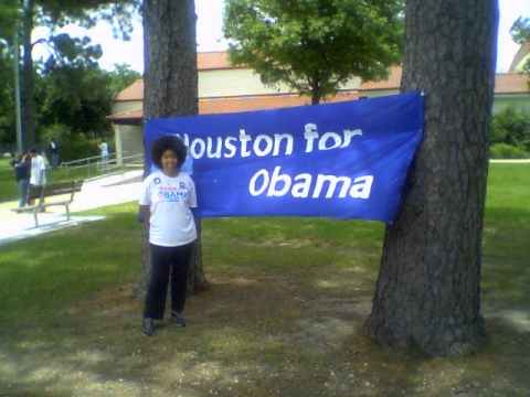 the boy is standing beside a sign for obama