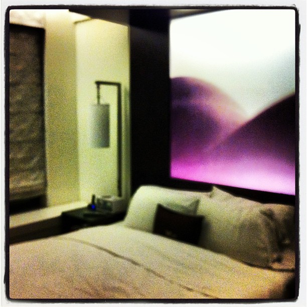 a bed with pillows and sheets and purple and white lights