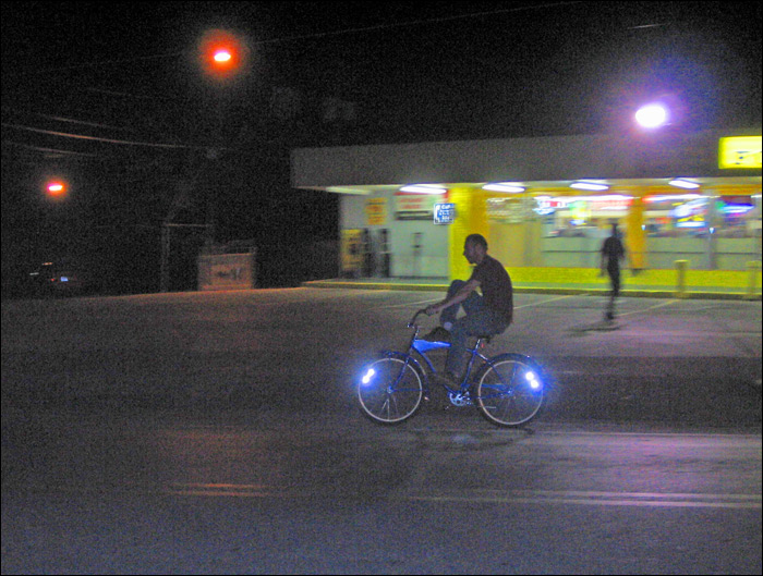 two people riding a blue bike at night