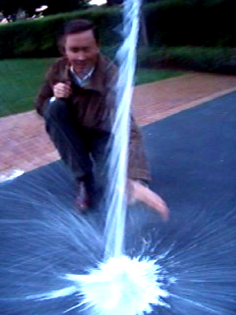 a man kneeling down with water spraying from his mouth