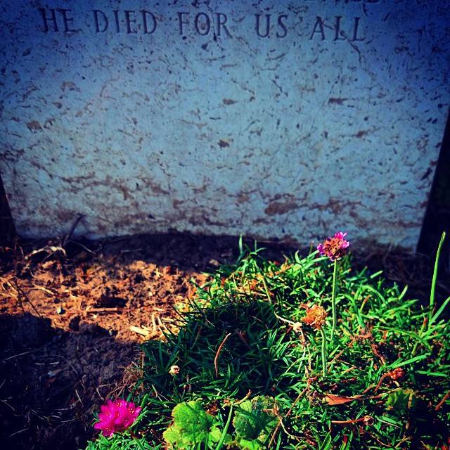 a gravestone in the grass with a sign above it