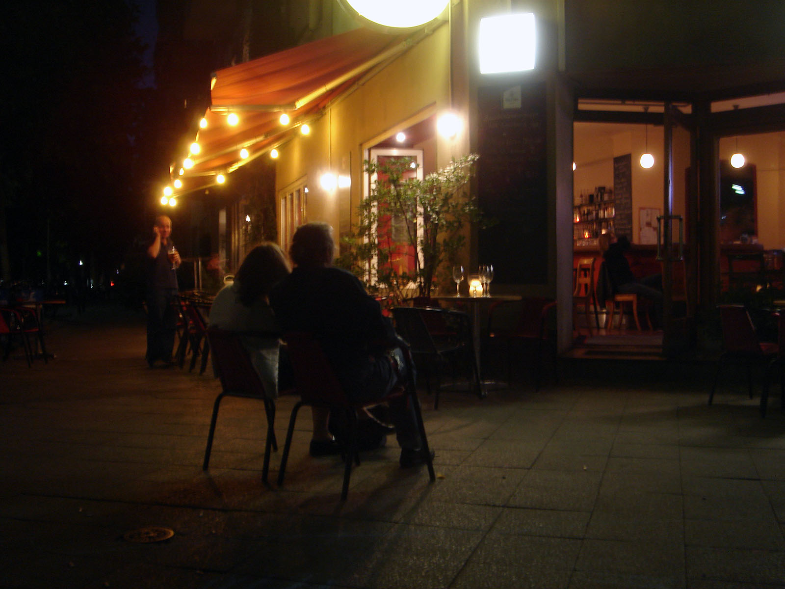 people sit at a small cafe during the night