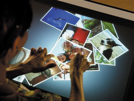 a person holds their hands up to touch a television screen with several images on it