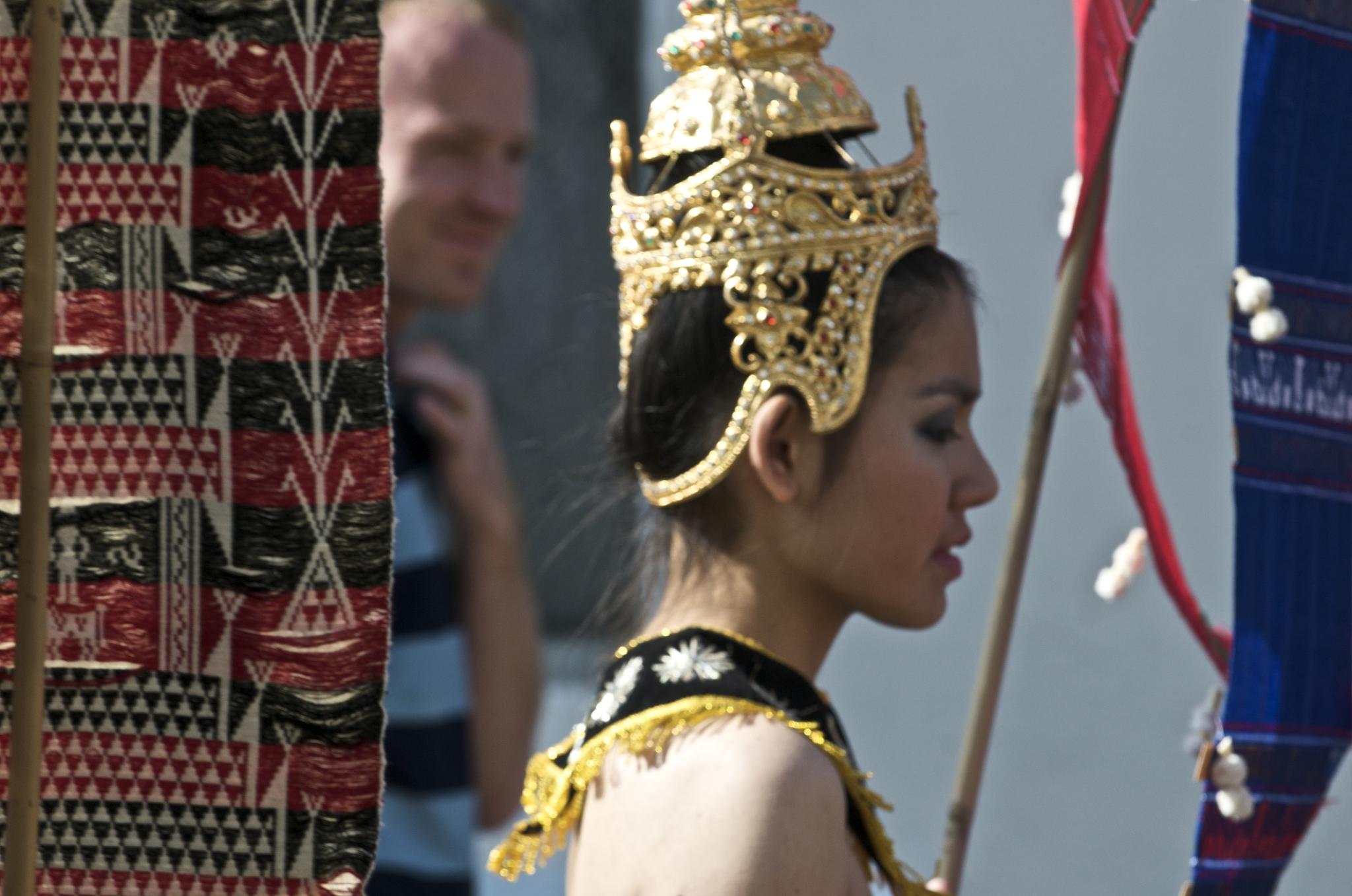 a woman wearing gold is holding a red umbrella