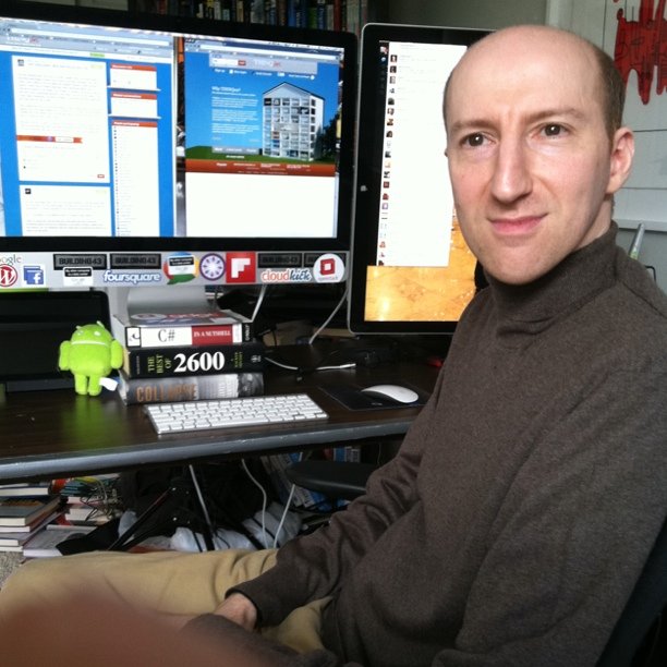 a man sitting at his desk in front of two computers